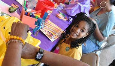 Child smiling in front of craft activity at the Japanese American National Museum during the 2023 Natsumatsuri Family Festival